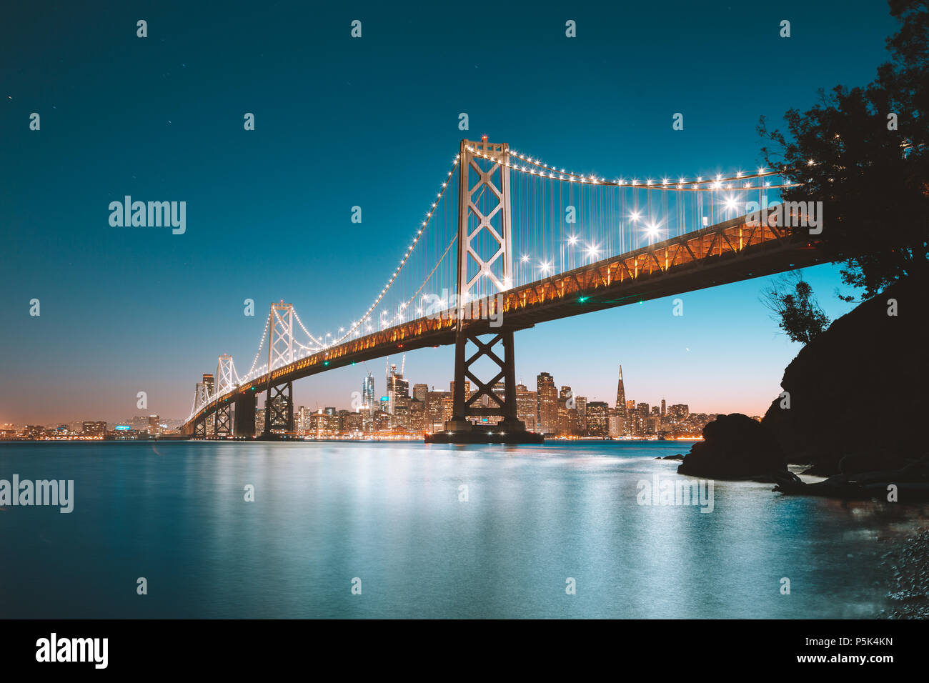 Klassische Panoramablick auf San Francisco Skyline mit berühmten Oakland Bay Bridge leuchtet in schönen Abend dämmerung Dämmerung im Sommer Stockfoto