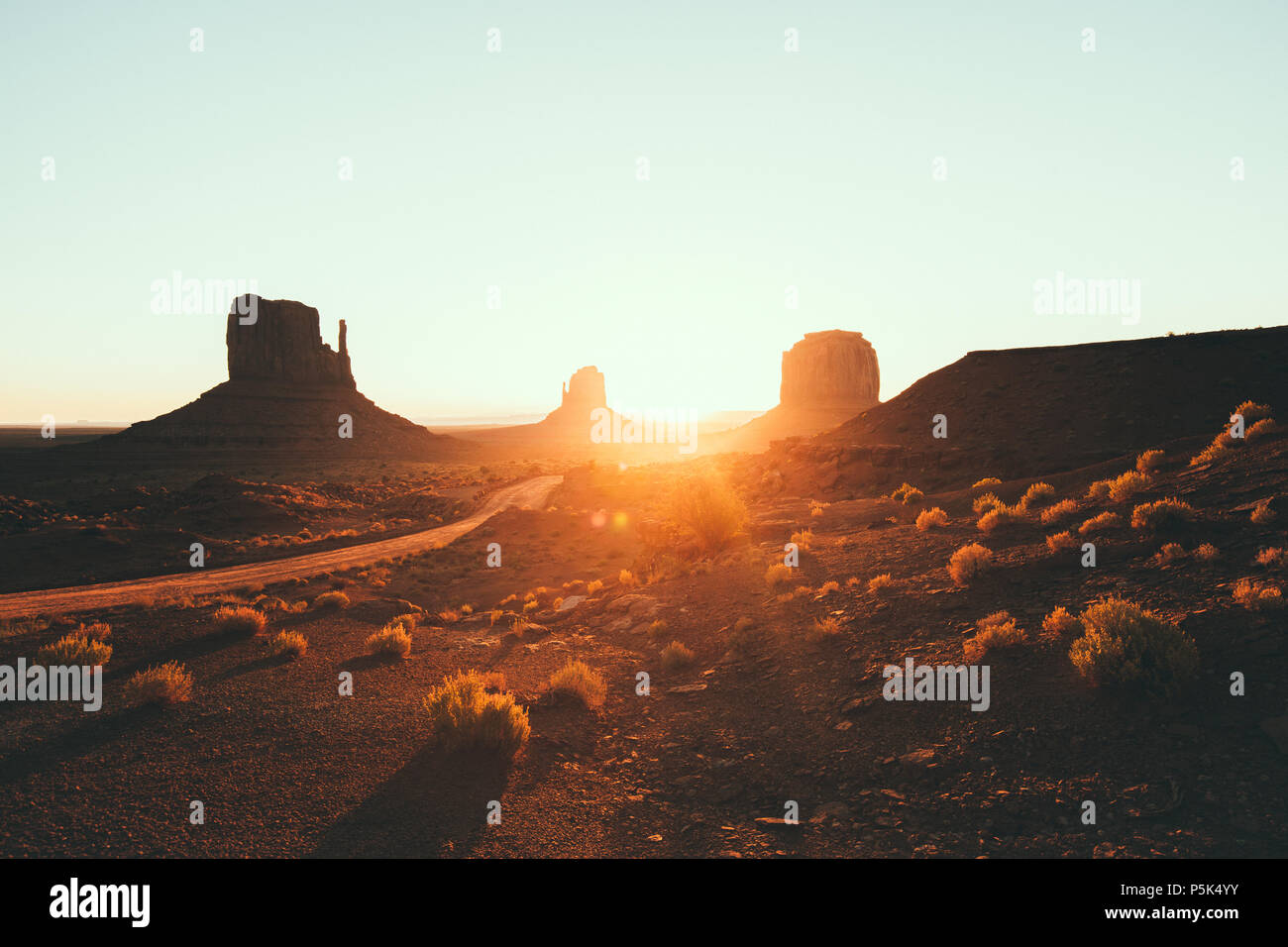 Klassische Ansicht des malerischen Monument Valley mit dem berühmten Fäustlinge und Merrick Butte im schönen goldenen Morgenlicht bei Sonnenaufgang im Sommer mit retro vin Stockfoto