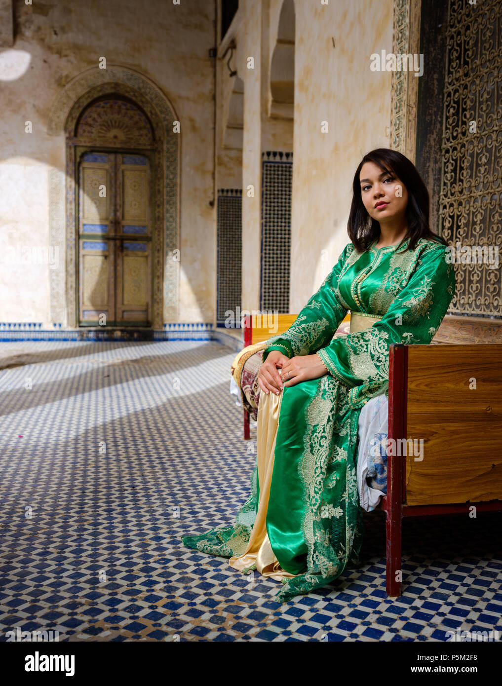 FEZ, MAROKKO - ca. April 2017: Junge marokkanische Frau in traditioneller Kleidung durch ein Fenster im El Glaoui Palast posing Stockfoto