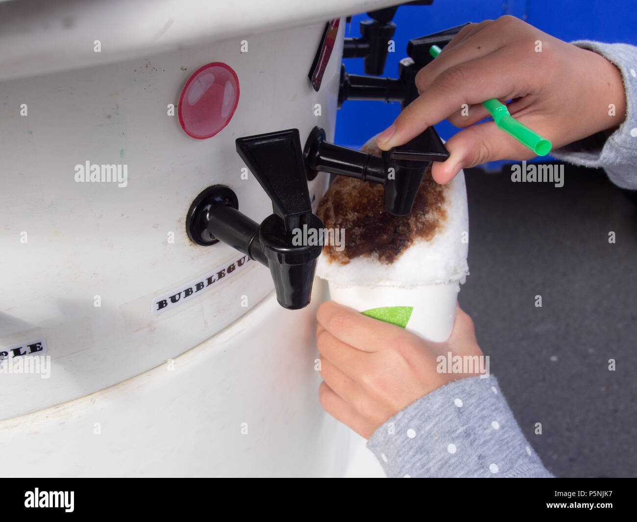 Kind setzen Aromastoffe auf eine Tasse rasiert Eis Stockfoto