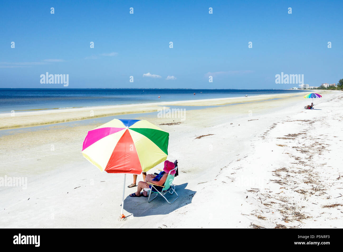 Florida, Fort Ft. Myers Beach, Newton Beach Park, Golf von Mexiko, Küste, Sand, farbenfroher Sonnenschirm, Frau weibliche Frauen, Schatten, Öffentlichkeit, Wasser, FL170925093 Stockfoto