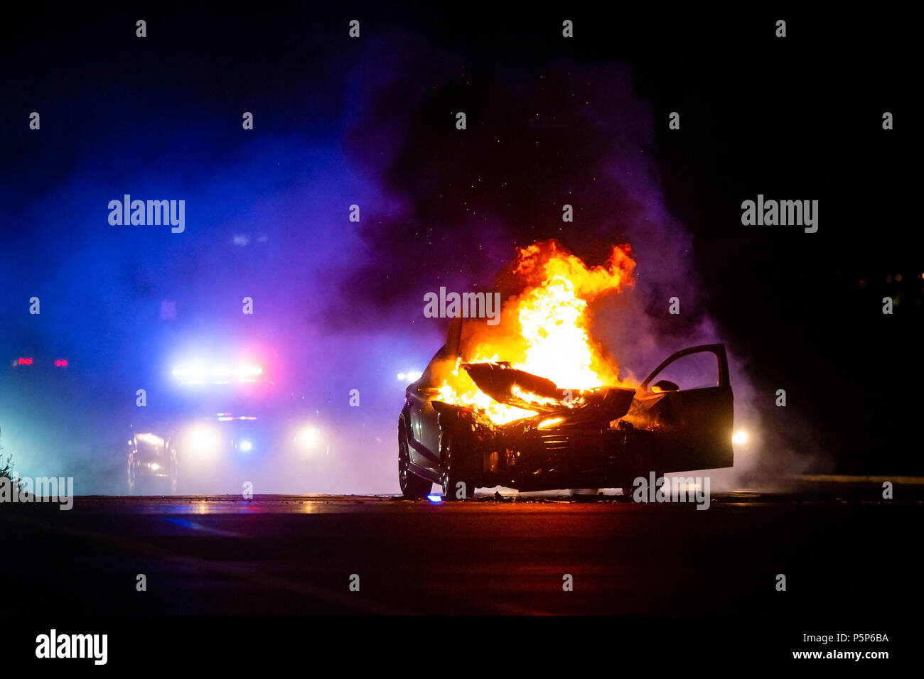 Auto auf Feuer in der Nacht mit der Polizei Lichter im Hintergrund bei Nacht Stockfoto