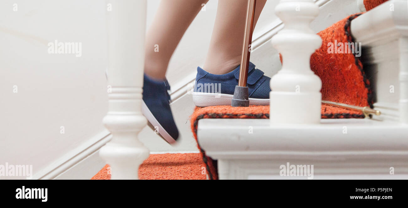 Ältere Frau geht die Treppe hinauf, mit Lager, ältere Person auf Treppen mit Stick Stockfoto