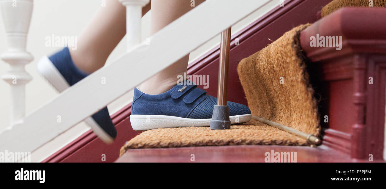 Ältere Frau geht die Treppe hinauf, mit Lager, ältere Person auf Treppen mit Stick Stockfoto