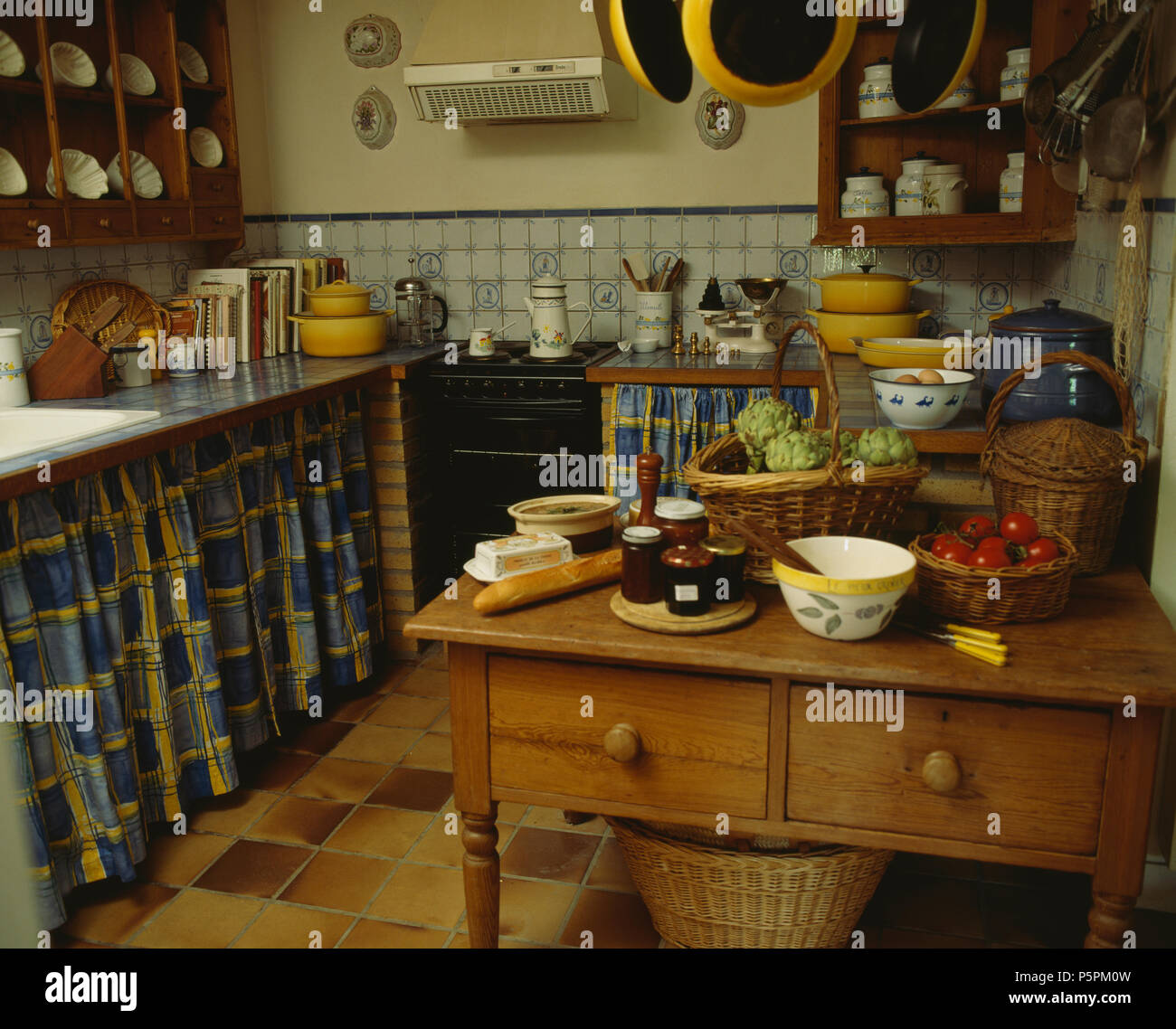 Kiefer Tisch in altmodische Cottage Küche mit gemusterten blauen Vorhängen unter Arbeitsplatten Stockfoto