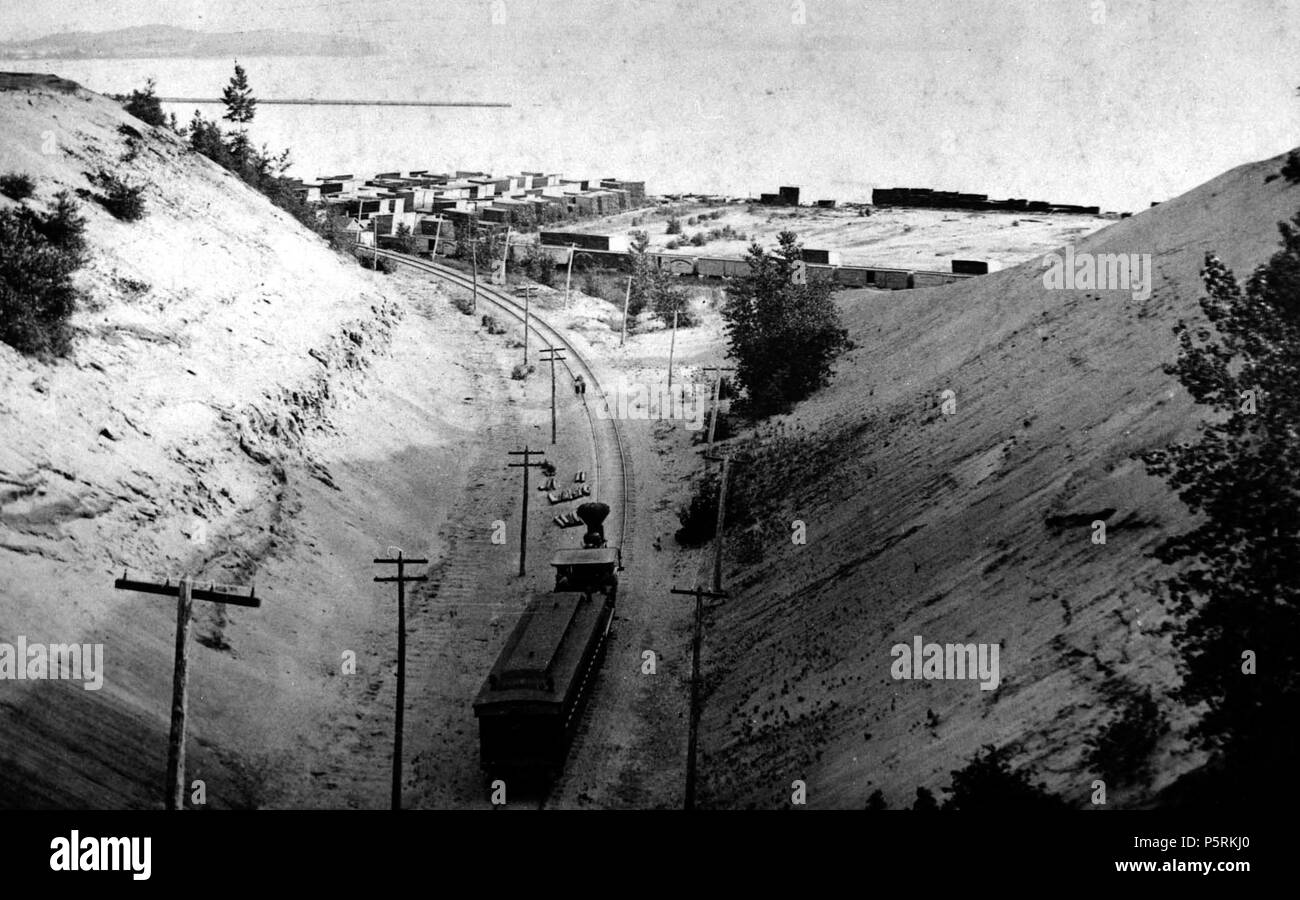 N/A. Deutsch: Das historische Bild zeigt einen Zug von einer Dampflokomotive auf einer Spur durch einen tiefen Schnitt in Sand gehen gezogen (unter der North Avenue, ca. 1860-1880) hinterlegt in den Lake Champlain Vermont oder das Meer am Ende der letzten Eiszeit. Es gibt Versorgungsleitungen und Polen entlang der Schiene und Bauholz auf der Pier bis in Lake Champlain. Der Wellenbrecher sichtbar ist. Einige Betten im Sand ausgesetzt. Die 1860er-1880. Unbekannt 251 Burlington Eisenbahntunnel, in Richtung Südwesten nach Burlington Harbor Stockfoto