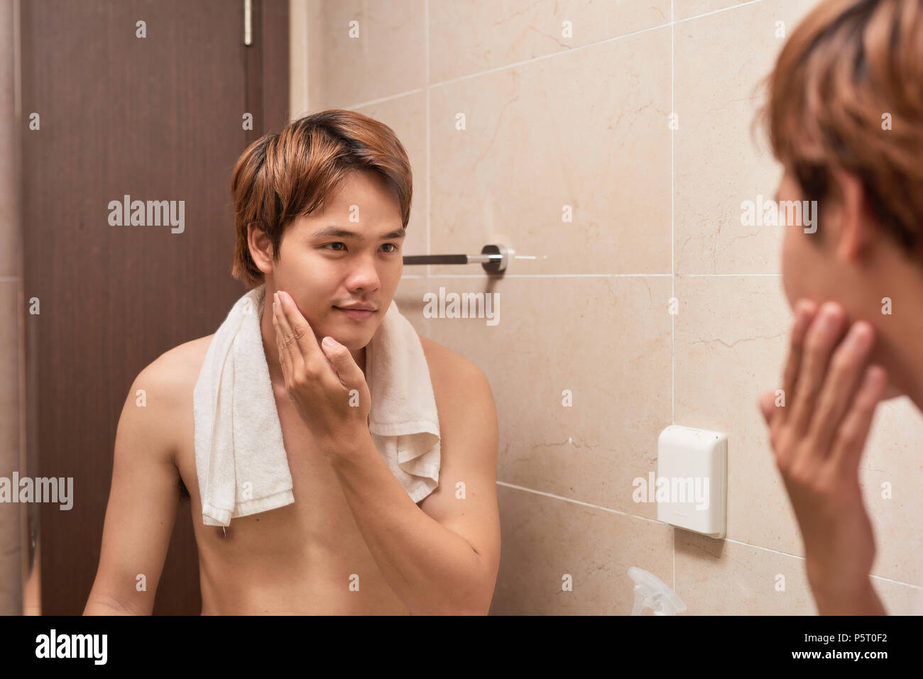 Männliche Schönheit. Die Jungen gut aussehenden asiatischer Mann seinem glatten Gesicht nach der Rasur berühren. Stockfoto