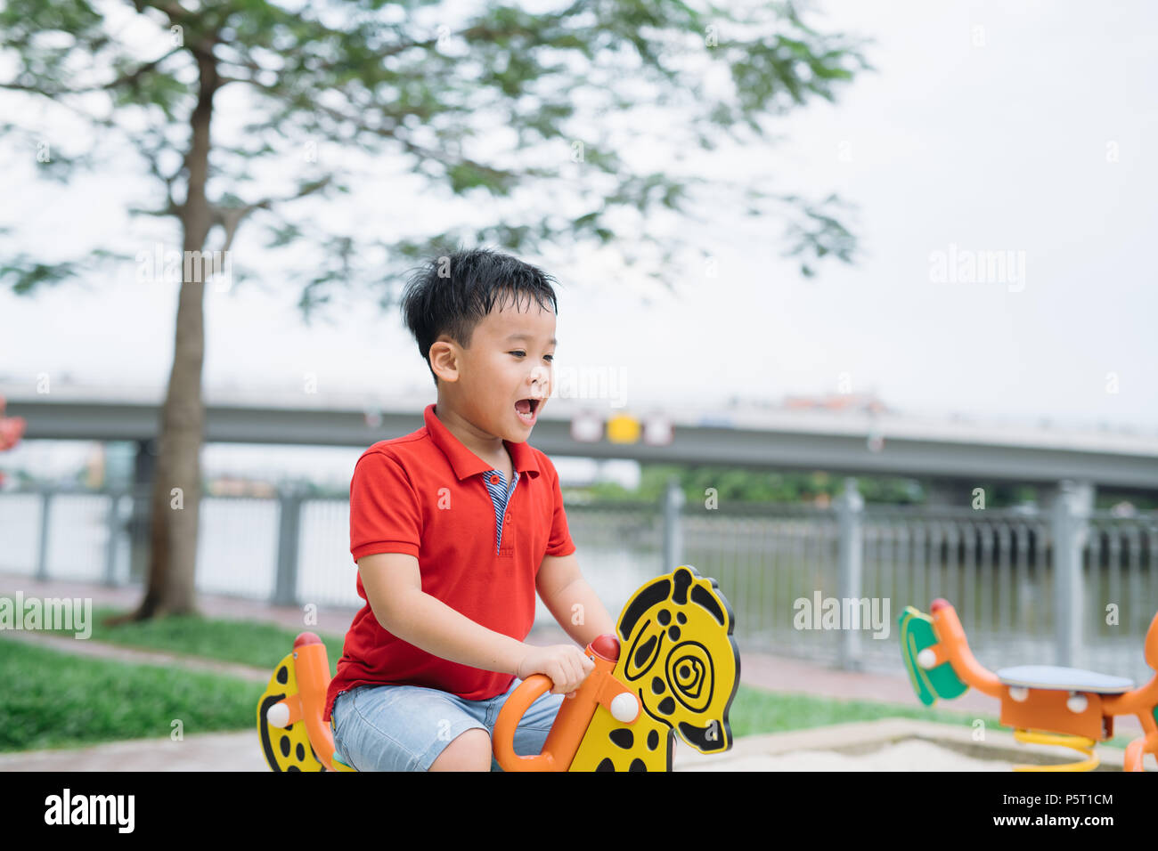 Asiatische Vietnamesischen schöner Junge sitzt auf Wippe am Spielplatz im Freien Stockfoto