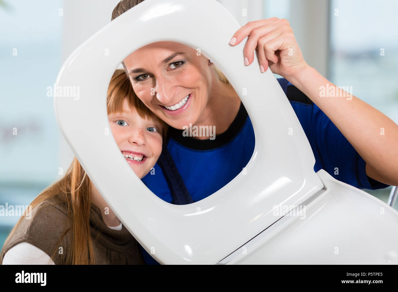 Porträt einer Frau und ihrer Tochter auf Kamera über einen WC-Sitz Stockfoto