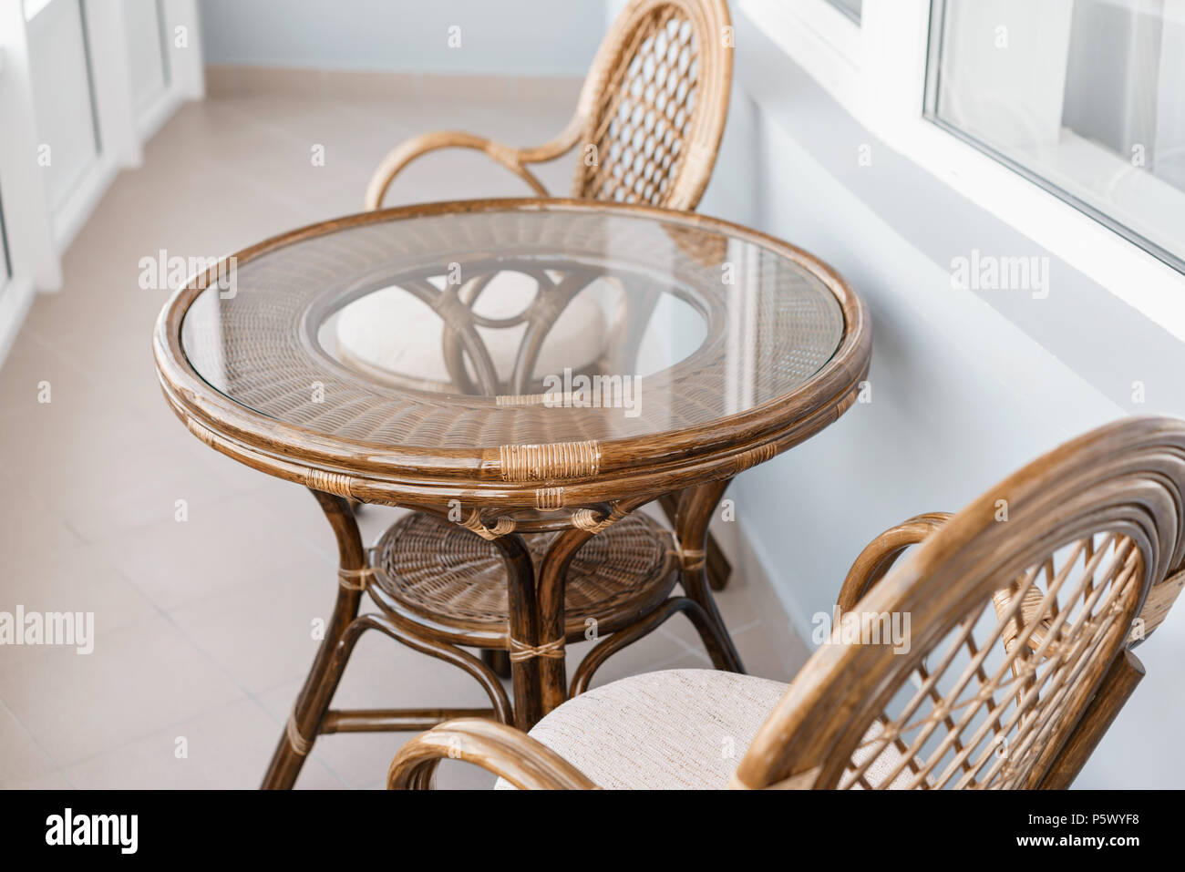 Glas Tisch und Rattan rattan Sitz Stuhl. Korbmöbel rattan Tisch zwei Stühle  in der Nähe der Fenster auf dem Balkon Stockfotografie - Alamy