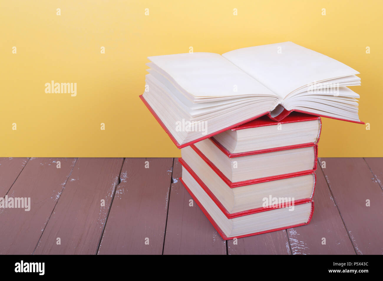 Wissenschaft und Bildung - Stapel Gruppe von roten Bücher einer leeren, oben offenen Vorderansicht auf dem Holztisch und gelben Hintergrund. Stockfoto