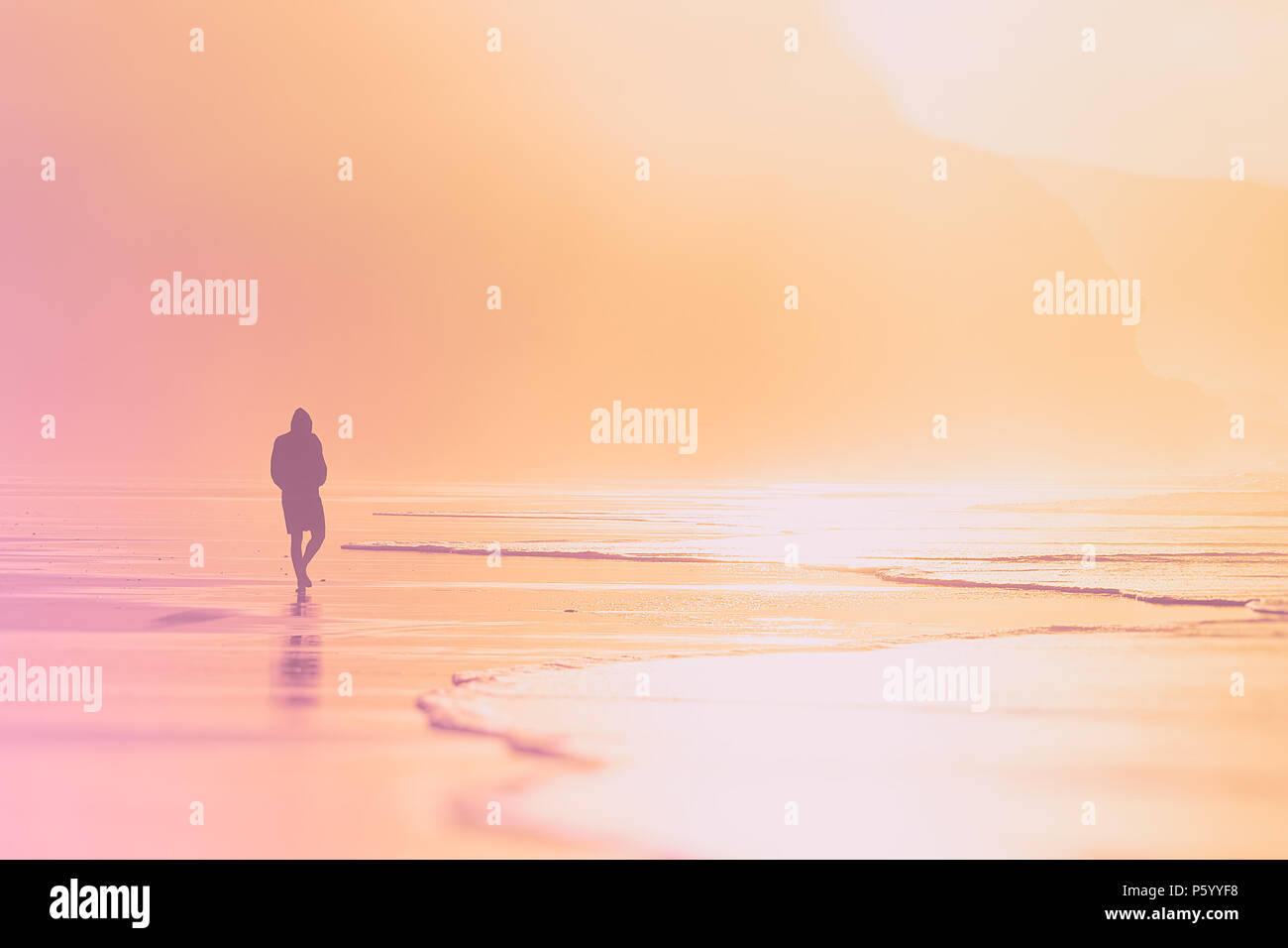 Einsame Person zu Fuß am Strand im Sonnenuntergang Stockfoto