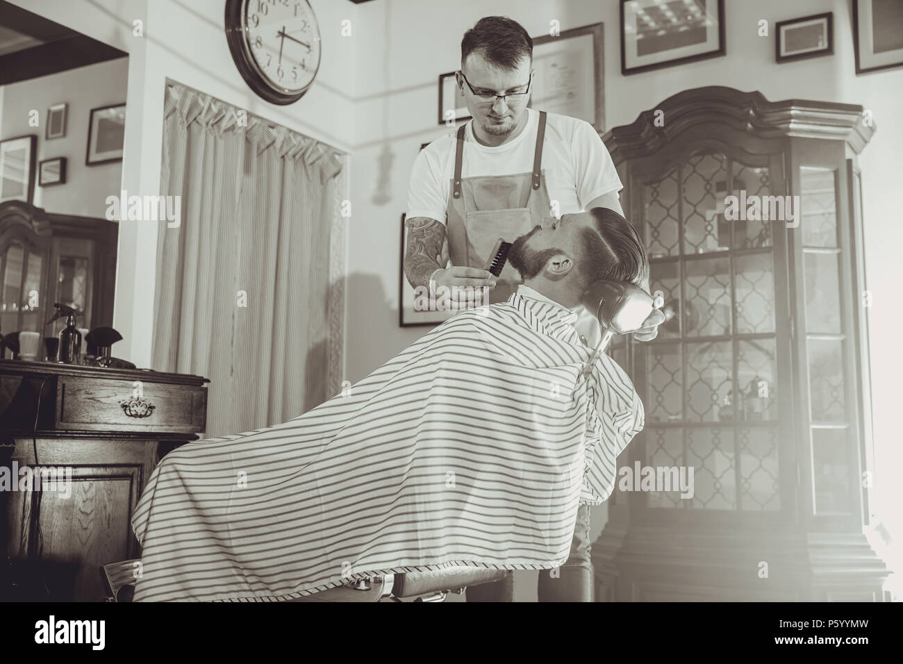 Friseur während der Arbeit in seinem Friseur. Bild in Schwarz und Weiß Stilisierung Stockfoto