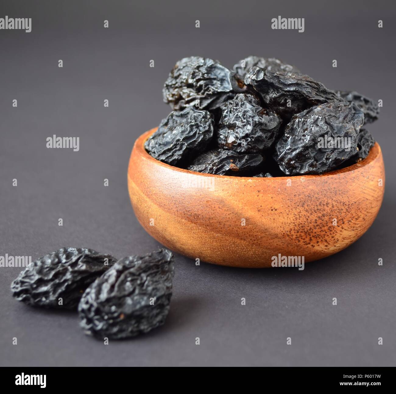 Pflaumen in Houten mit Wassertropfen auf schwarzem Hintergrund Stockfoto