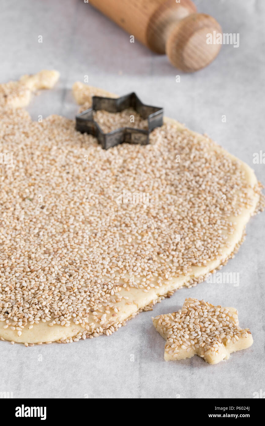 Schneiden sternförmiges Gebäck aus Hefeteig mit Sesam auf Küchenpapier bestreut. Stockfoto