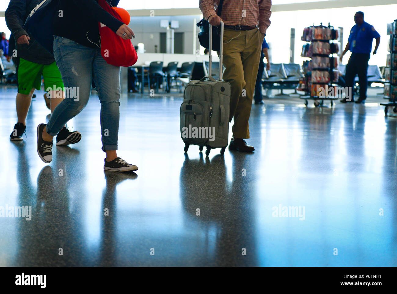 Ein Blick auf die Leute, einige von der Taille, Ihren Weg durch einen Flughafen Terminal mit reflektierenden Etagen, das Gepäck zu ziehen und aus dem airl Stockfoto