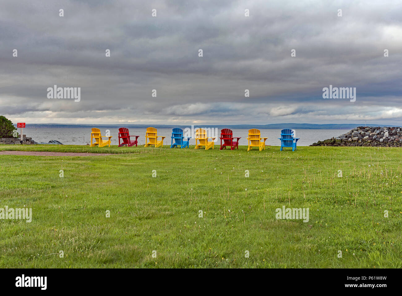 Bunte Stühle mit Blick auf die Bucht von Fundy in Alma New Brunswick, Kanada. Stockfoto