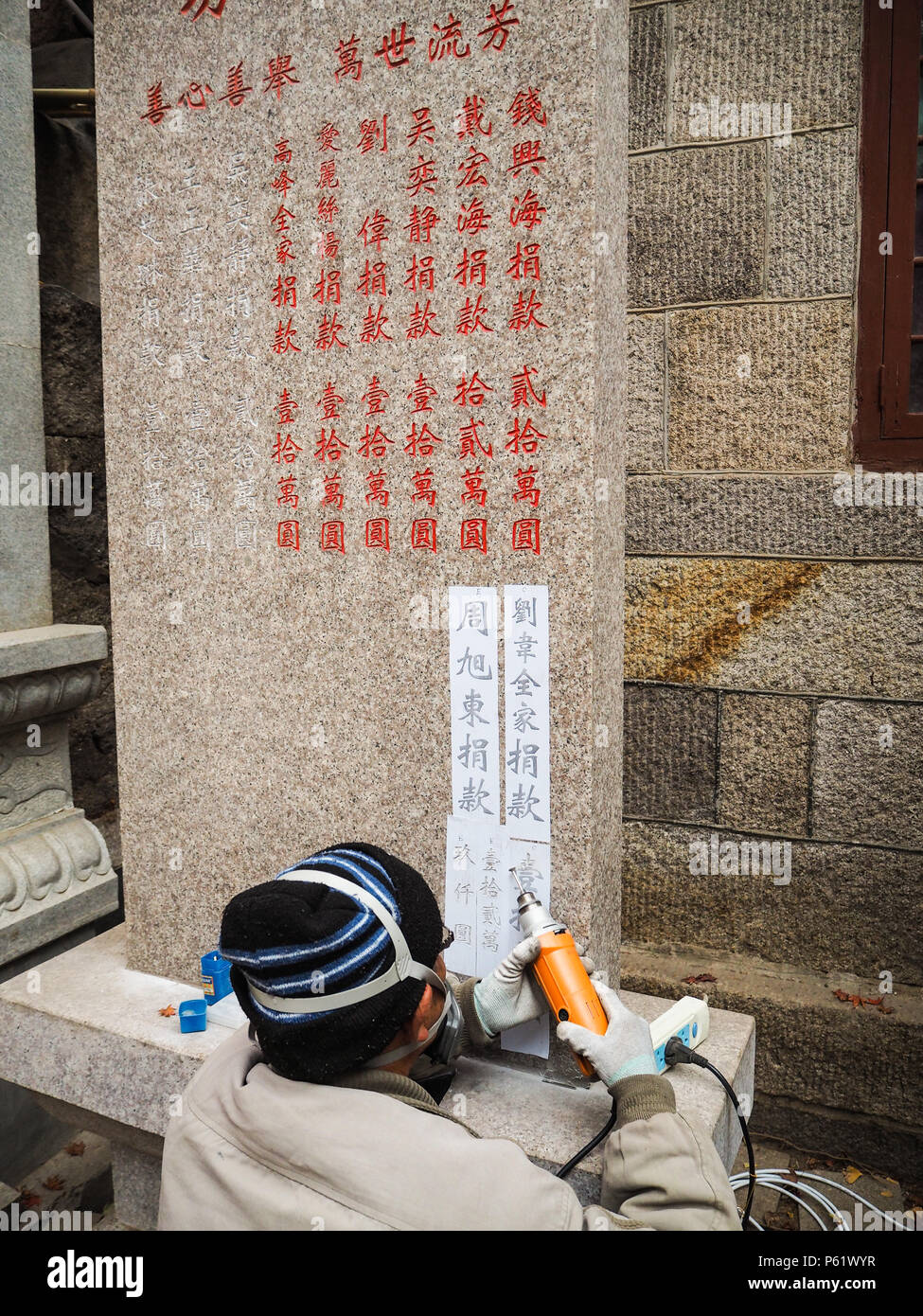Qingdao, China - Dezember 2017: älterer Mann carving Namen und Spende auf s im Taiqing Tempel Stele, Laoshan Stockfoto