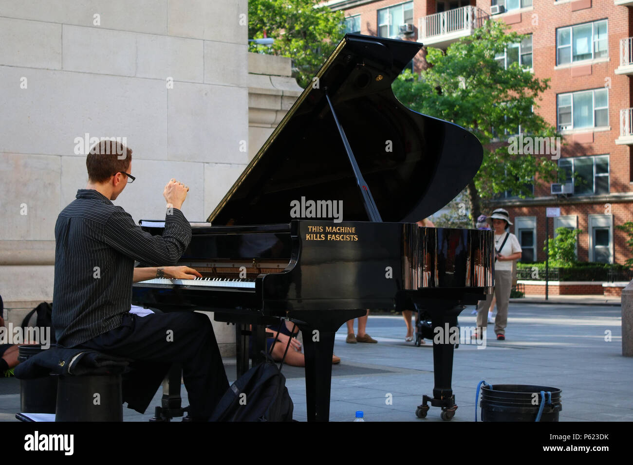 NEW YORK, NY - 2. JULI: Diese Maschine tötet Faschisten - Col Straßenmusik durch das Spielen von Grand Piano unter Washington Square Park arch im West Village, Manhattan o Stockfoto