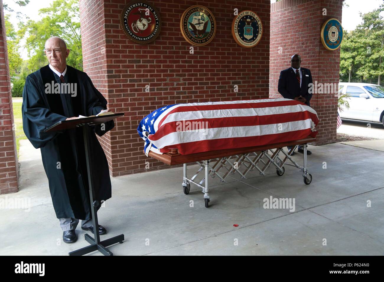 In der Saint Helena’s Church in Beaufort, South Carolina, wird eine zeremonielle Beerdigung für einen Captain der U.S. Navy durchgeführt, der 30 Jahre im Navy and Marine Corps diente. Die Zeremonie umfasst einen Kaplan, eine militärische Ehrenwache, eine Flaggenpräsentation und traditionelle militärische Ehren. Die Teilnehmer, darunter Familie, Militärangehörige und Vertreter der Gemeinde, beteiligen sich an der Auszeichnung und Würdigung des Dienstes, der Führung und des Engagements des Offiziers. Stockfoto