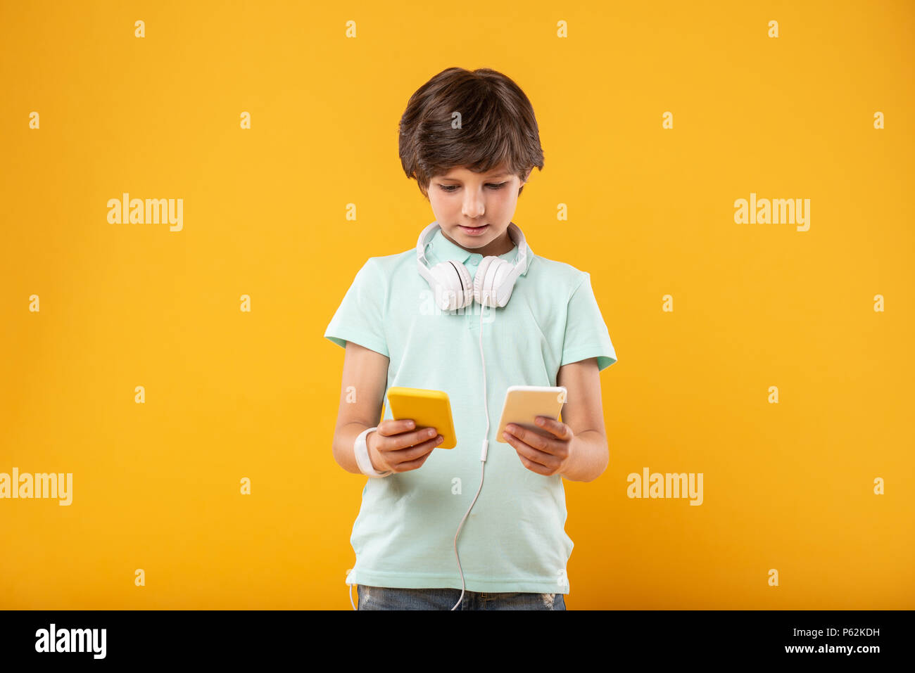 Konzentriert Schüler halten zwei Telefone Stockfoto