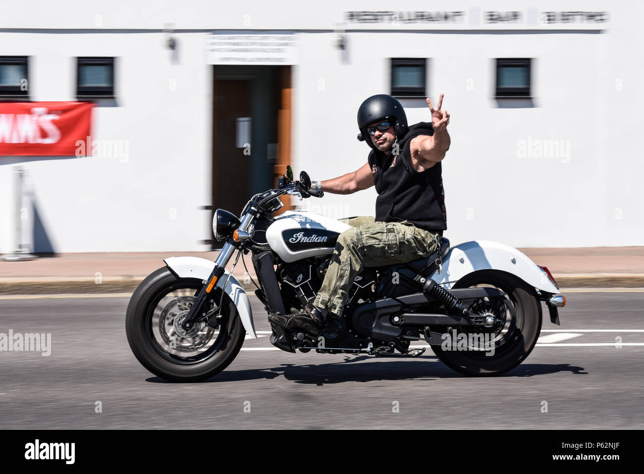 Motorradfahrer Reiten entlang der Küste Southend On Sea, Essex, Großbritannien auf ein indisches Motorrad. Die Unterzeichnung eines V für Sieg hand Signal Stockfoto