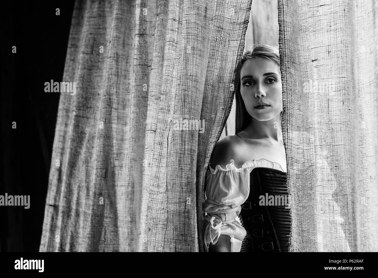 Eine Renaissance Faire Schauspieler stellt in einem Türrahmen mit einem sackleinen Vorhang Stockfoto