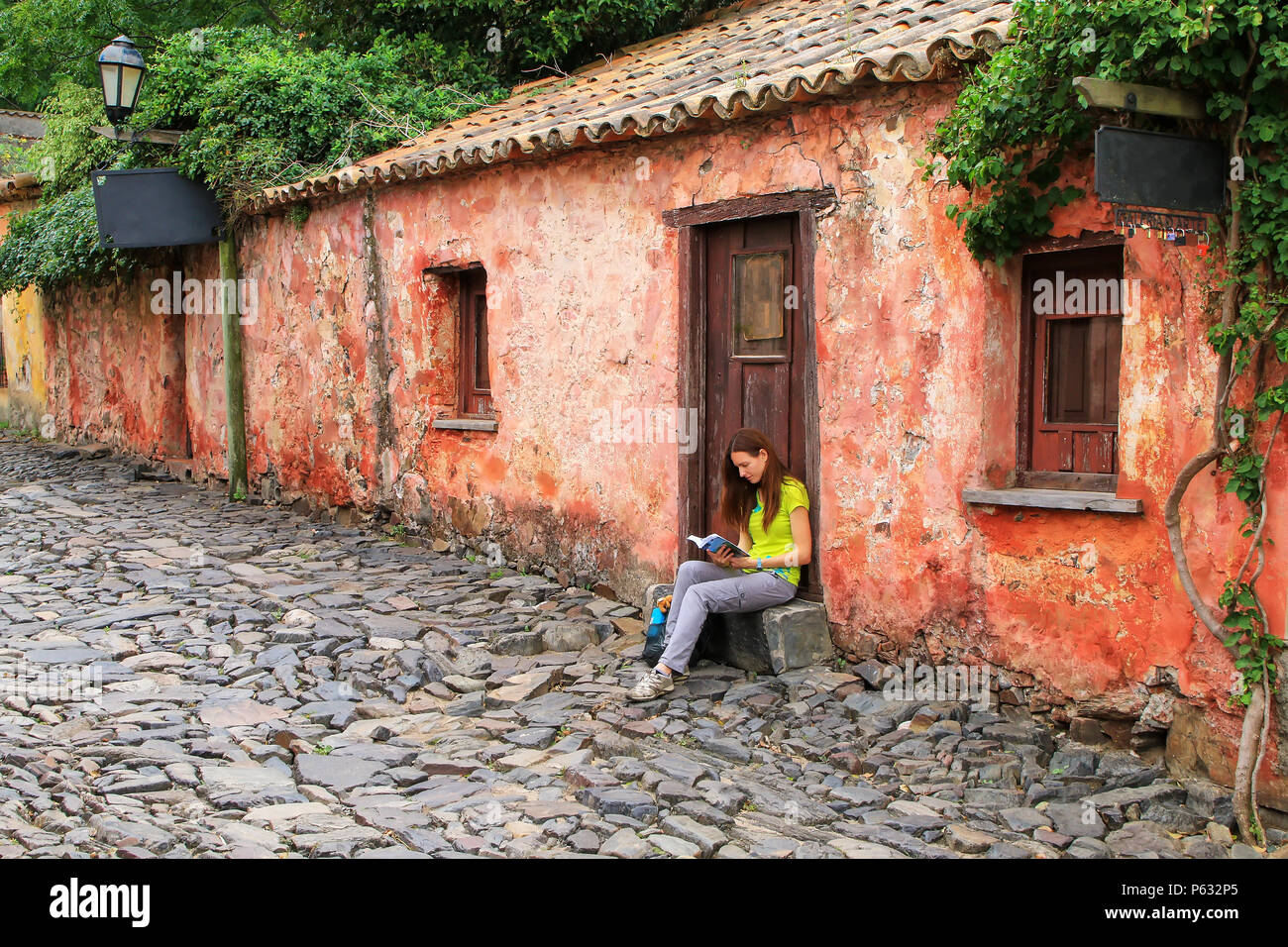 Junge Frau sitzt auf der Calle de Los Suspiros (Straße der seufzt) in Colonia del Sacramento, Uruguay. Es ist eine der ältesten Städte in Uruguay Stockfoto