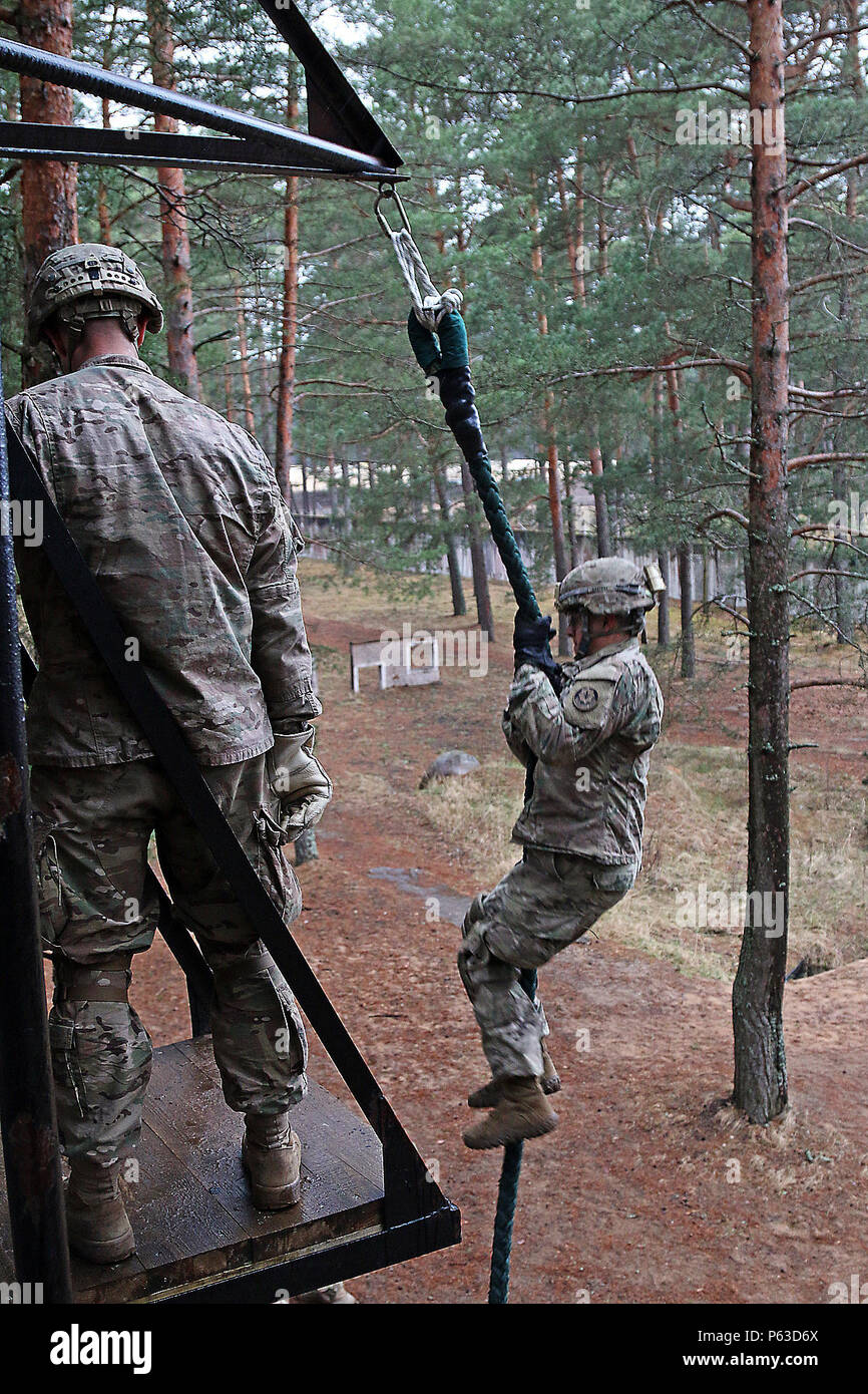 Ein Soldat an die Zentrale und Hauptverwaltung Truppe, 3 Staffel, 2. Reiterregiment zugeordnet rutscht ein Seil von einem Turm während der multinationalen schnellen Seil Einarbeitung training April 20, bei Adazi Militärbasis, Lettland. Lettische Soldaten nahmen ebenfalls an der Übung als Teil der Sommer Schild XIII, einer zwei Wochen langen Interoperabilität Übung. Amerikanische Soldaten in der Region Unterstützung Betrieb Atlantic lösen sich Verbündeten aus Lettland, Kanada, Litauen und Deutschland für den jährlichen Schulungsveranstaltung. (U.S. Armee Foto von Sgt. Paige Behringer, 10 Drücken Sie Camp Headquarters) Stockfoto