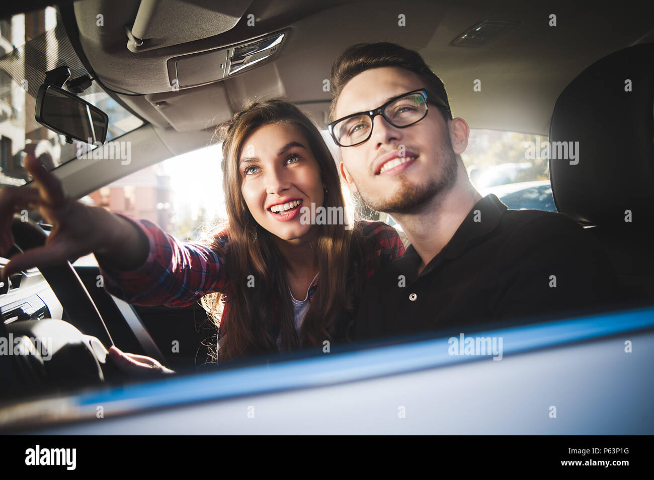 Genießen reisen. Schöne junge Paar saß auf dem Beifahrersitz und lächelnd, während gut aussehender Mann, der ein Auto fährt. Stockfoto