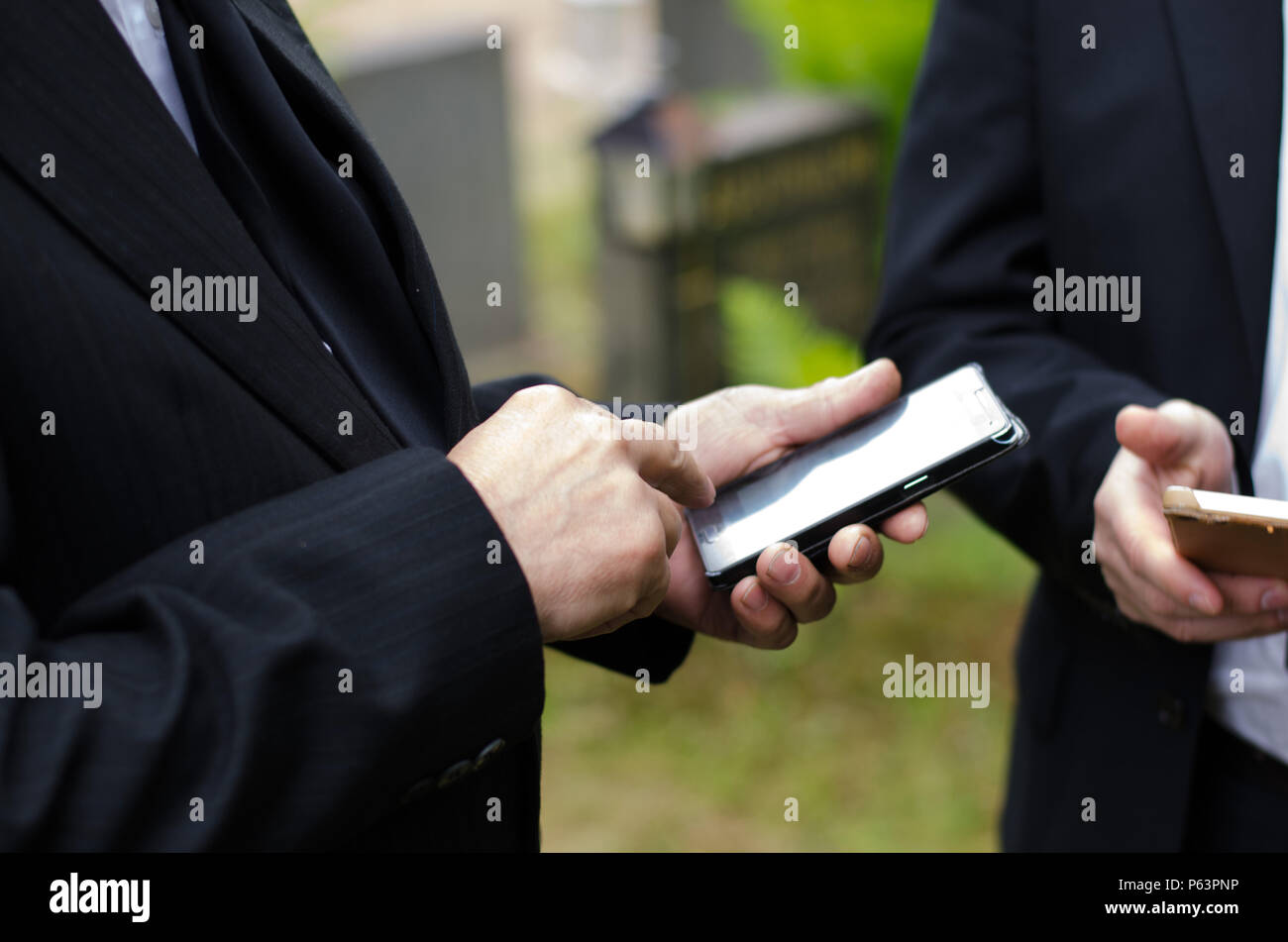 Älterer Mann im dunklen Anzug mit einem Mobiltelefon Stockfoto