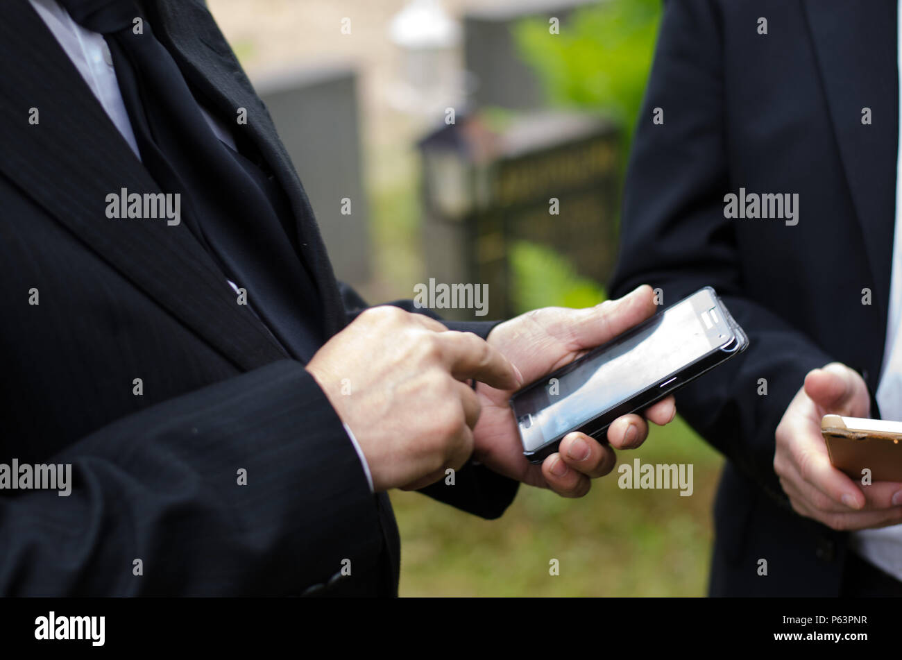 Älterer Mann im dunklen Anzug mit einem Mobiltelefon Stockfoto
