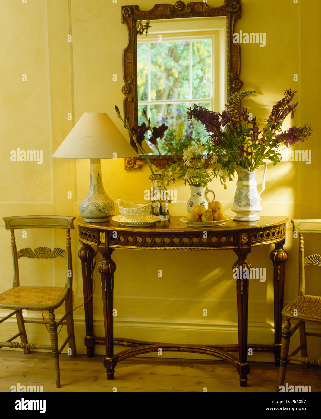 Spiegel über antike Konsole Tisch mit Creme Lampe in gelb Land Halle Stockfoto