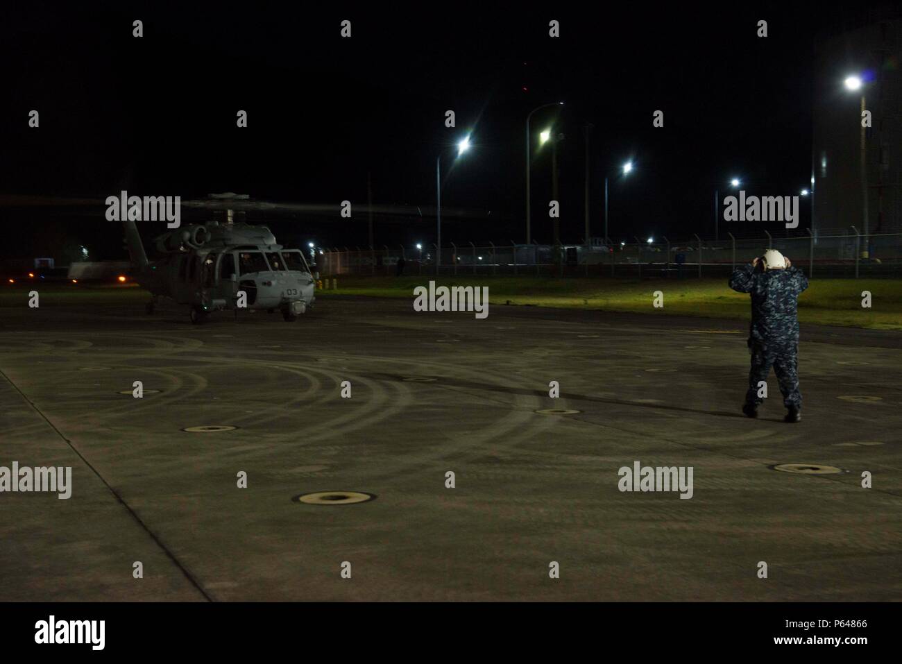 SASEBO, Japan (18. April 2016) Commander, U.S. Flotte Aktivitäten Sasebo Port Operations Officer Chief Warrant Büro Timothy Greene leitet einen Hubschrauber Meer bekämpfen Squadron (HSC) 25 MH-60 Seahawk-Hubschrauber auf dem Rollfeld Aufgewendete 18. April 2016. Der Hubschrauber aufgetankt und Personal gerne bei MV-22 Osprey Operationen aus dem Gefäß zur Unterstützung von Kumamoto Erdbeben Katastrophenhilfe für Japan Maritime Self-Defense Force Hubschrauber Zerstörer JS Hyuga (DDH 181) gebunden in Angriff genommen. Auf Antrag der japanischen Regierung ist US-Truppen in Japan Luftbrücke japanische Selbstverteidigung F unterstützen Stockfoto