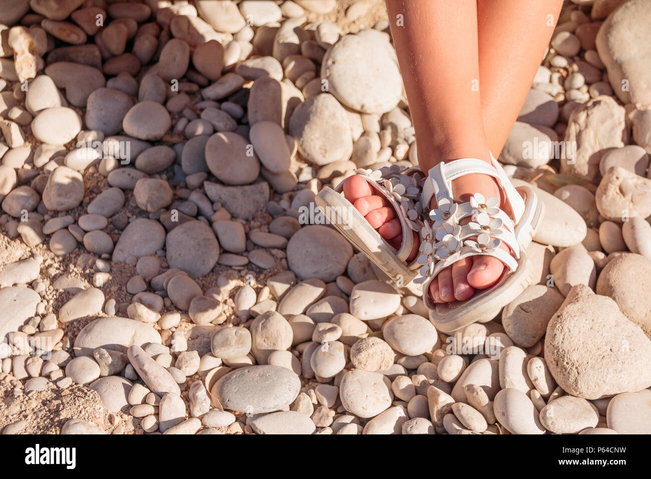 Kinder Sommer Sandalen. Baby Schuhe auf Steine Strand getrennt. Mädchen  weiß Mode Schuhe, Leder Sandale, Mokassins. Beine von einem kleinen Mädchen  in weißen Sandalen am Strand. Platz kopieren Stockfotografie - Alamy