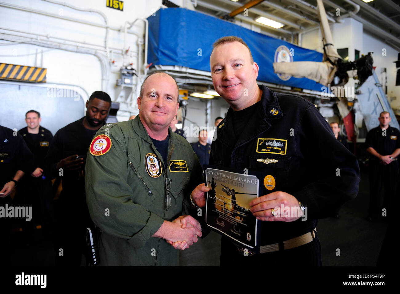 160408-N-VD 165-010 Arabische Meer (April 8, 2016) Kapitän Mike Ruth, kommandierender Offizier der Amphibisches Schiff USS Boxer (LHD4) stellt den eingetragenen Informationen Dominanz Kriegsführung Specialist Zertifikat zu Command Master Chief Matt Ruane während einer Kriegsführung pinning Zeremonie im Hangar Bay. Boxer ist das Flaggschiff der Boxer amphibische Gruppe und bereit, mit der begonnen 13 Marine Expeditionary Unit, ist zur Unterstützung der Maritime Security Operations und Theater Sicherheit Zusammenarbeit in den USA 5 Flotte Bereich der Operationen eingesetzt. (U.S. Marine Foto von Massenkommunikation Spe Stockfoto