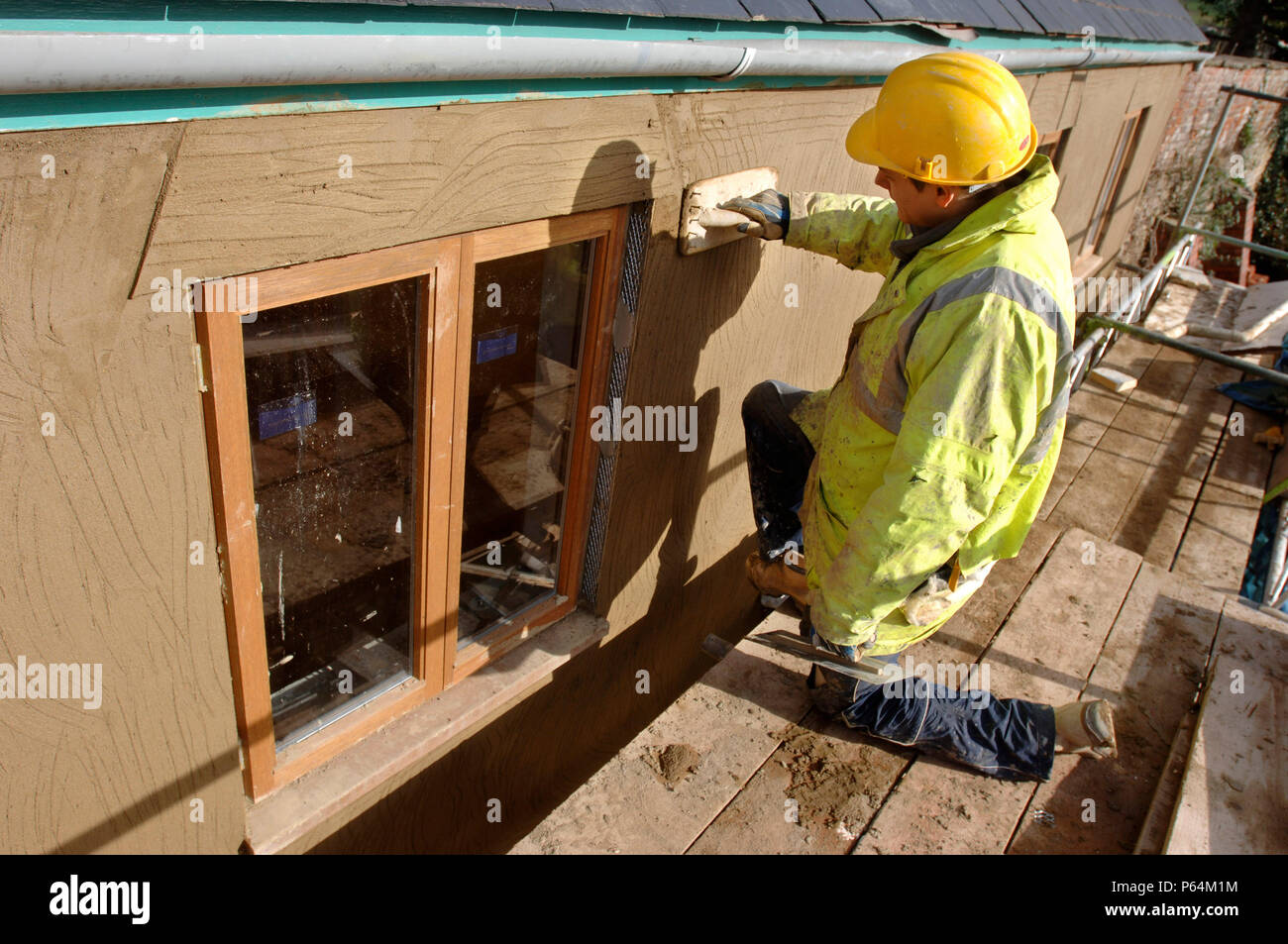 Ein gipser Rendering ein reibeputz beenden Um neue Hartholz Kastenfenster auf eine Hütte, Renovierung, Großbritannien Stockfoto