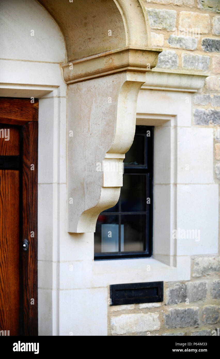 Maßgeschneiderte Stein gewölbt Konsolen unterstützen Mauerwerk umgibt auf ein renoviertes Bauernhaus Türöffnung mit einem Stein gewölbte Motorhaube, Großbritannien Stockfoto