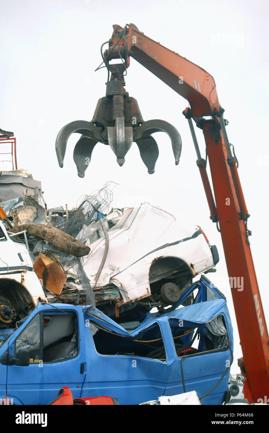 Mechanische Lader mit einem Enterhaken arm in einer Recyclinganlage am Anlegesteg in einem Hafen Newport, South Wales, Großbritannien Stockfoto