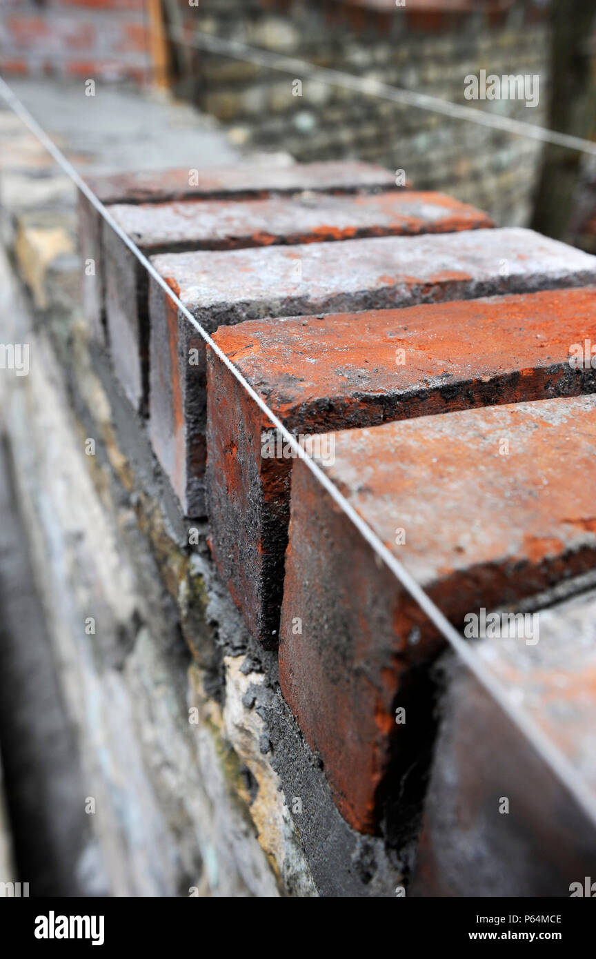Bau einer Gartenmauer mit Cotswold Stone und aufgearbeiteten roten Ziegeln UK Stockfoto