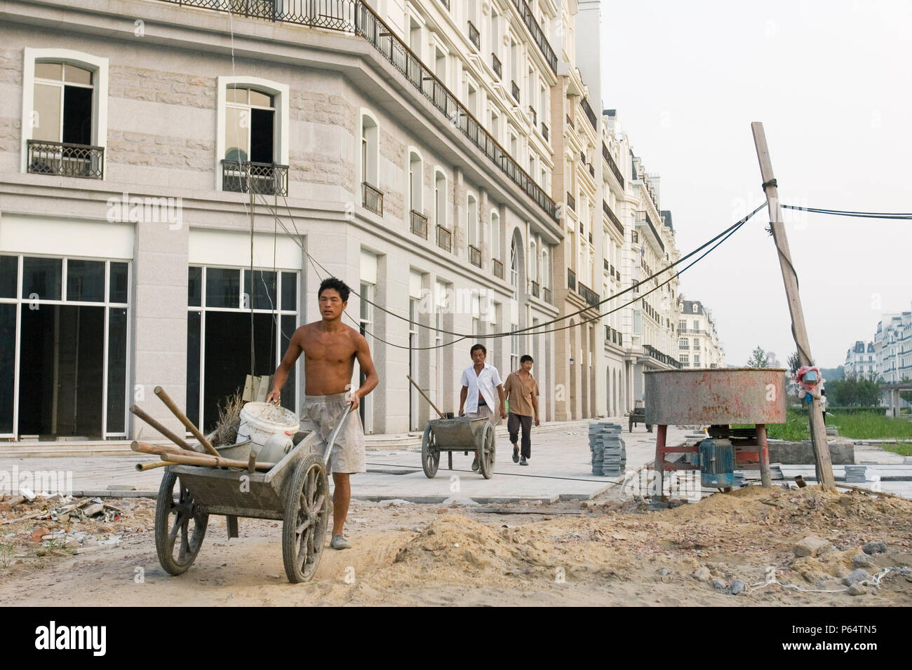 Chinesische Arbeiter Spaziergang durch Tiandu Cheng, einem Pariser-themed Wohnentwicklung im Bau in Hangzhou, China, 11. August 2007. Die deve Stockfoto