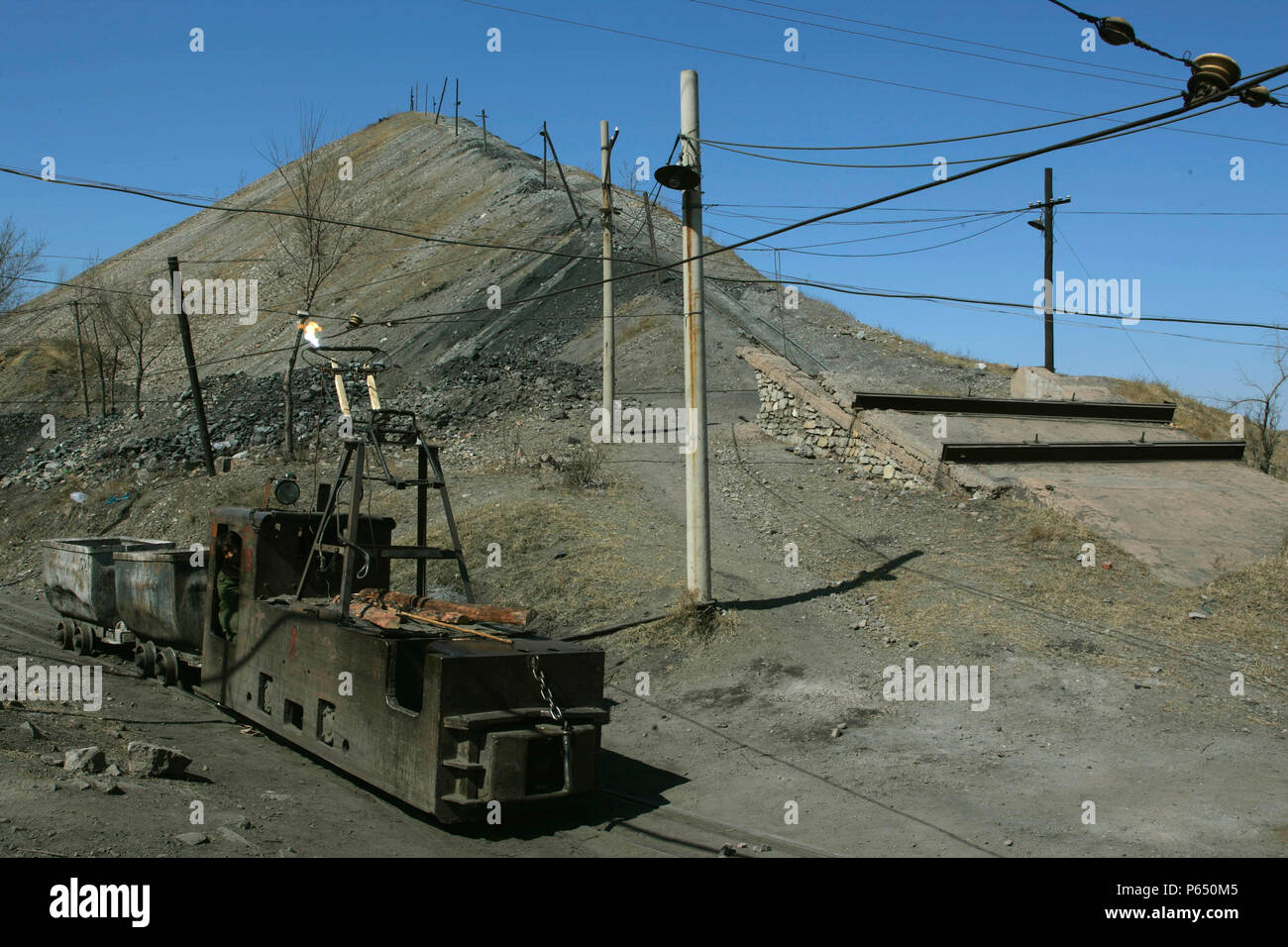 Ein 600 mm Spurweite overhead elektrische Lokomotive kommt an der Schlacke Tipp an Sinjiazi mit Raub aus den Minen Stockfoto
