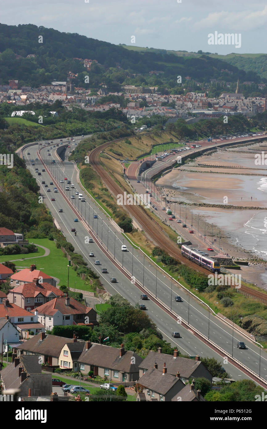 Eine erste North Western Class 175 mit einem Service von Holyhead führt entlang der A55 Trunk Road, wie es Röcke der Küste von Nordwales in Colwyn Bay. Juli Stockfoto
