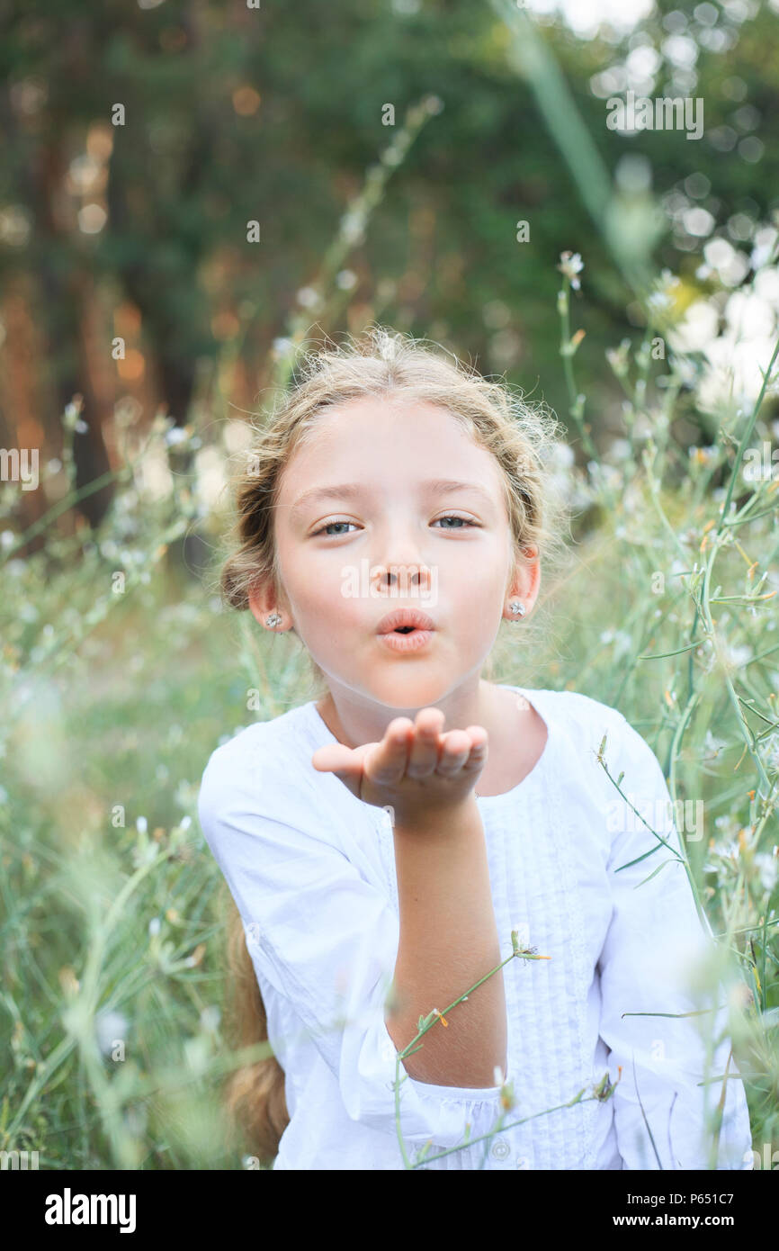 Porträt eines niedlichen kleinen Mädchen sendet einen Kuss auf die Natur, Blumen. Stockfoto