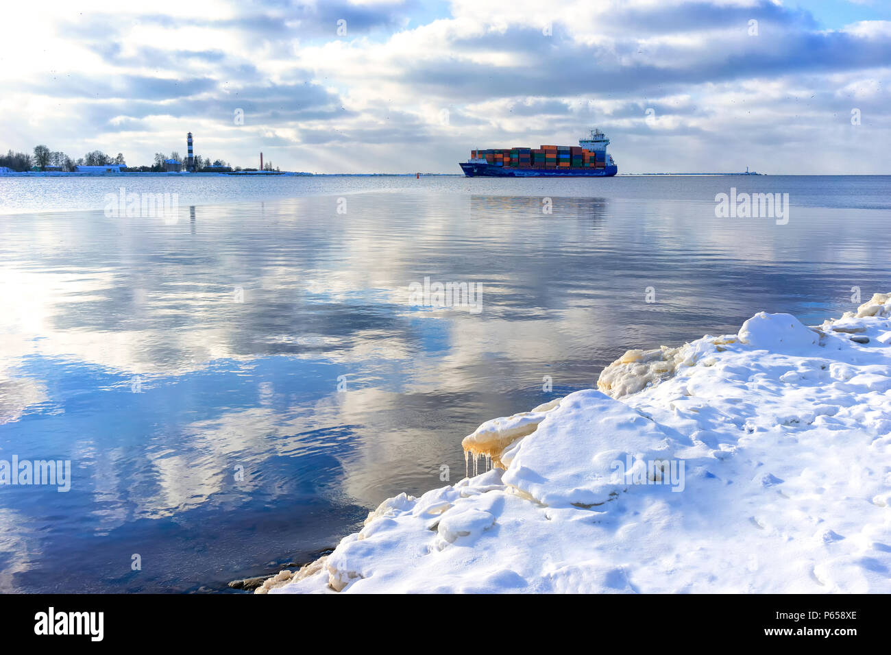 Ein Frachtschiff in der Mündung des Flusses Daugava Vergangenheit der Leuchtturm auf ein Wintertag in Lettland Stockfoto