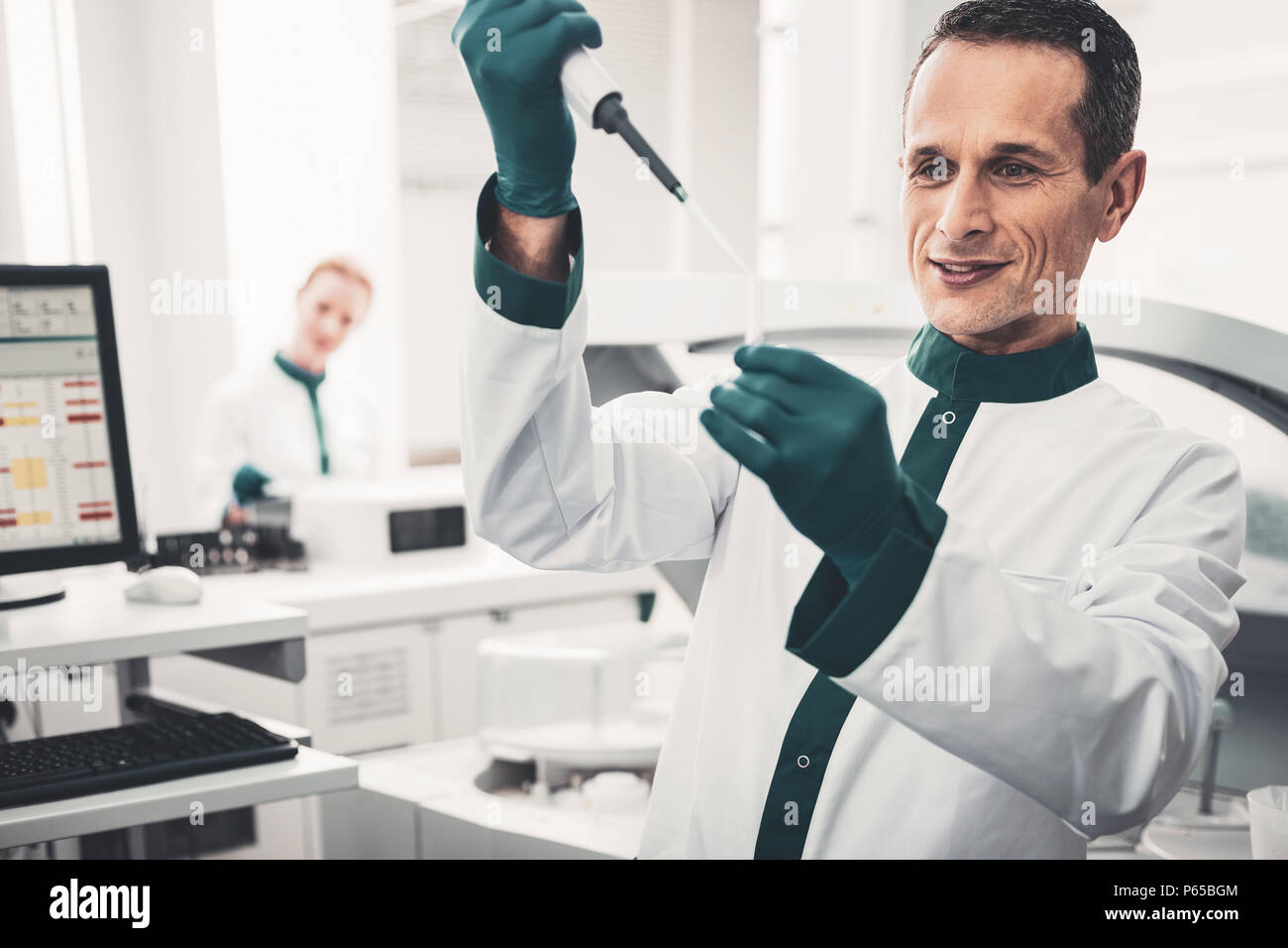 Portrait von konzentriertem Arzt mit Pipette und Reagenzglas Stockfoto