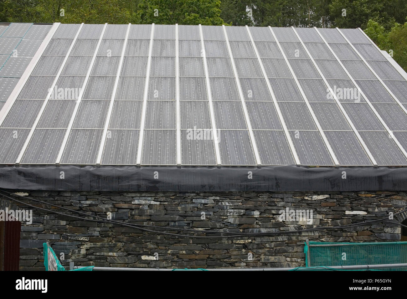 Ein Gebäude, das mit Solarenergie Photovoltaik Sonnenkollektoren auf dem Dach am Zentrum für Alternative Technologie in Petworth, Powys, Wales, Großbritannien Stockfoto