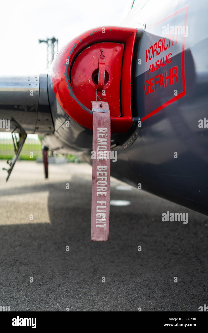 Entfernen Sie vor dem Flug eine Band auf einem Düsenflugzeug. Close-up. Die Inschrift in deutscher Sprache: Aufmerksamkeit. Gefährlich für das Leben. Stockfoto