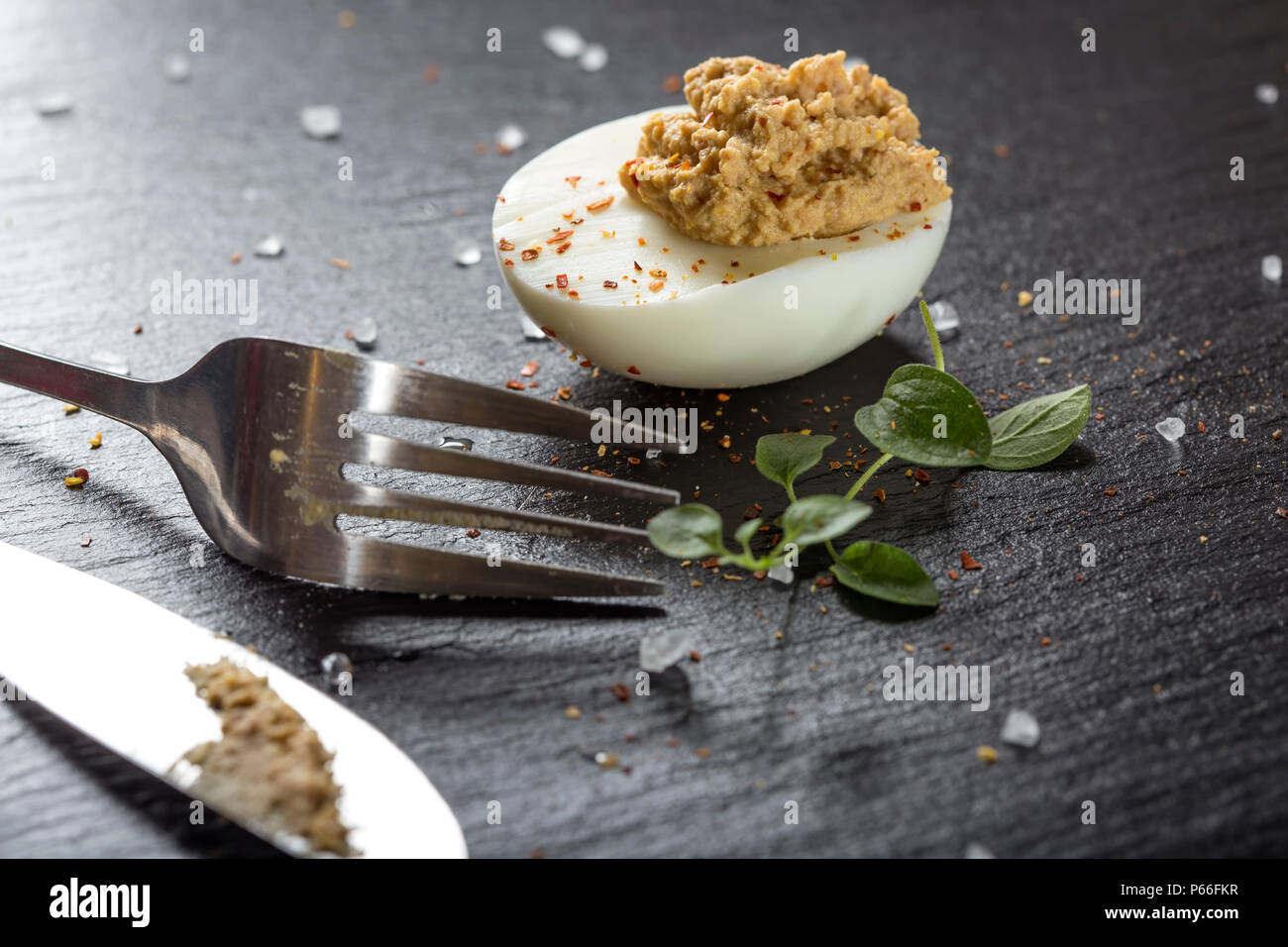 Gefüllte Eier mit Messer und Gabel auf dunklem Schiefer, Ansicht schließen Stockfoto