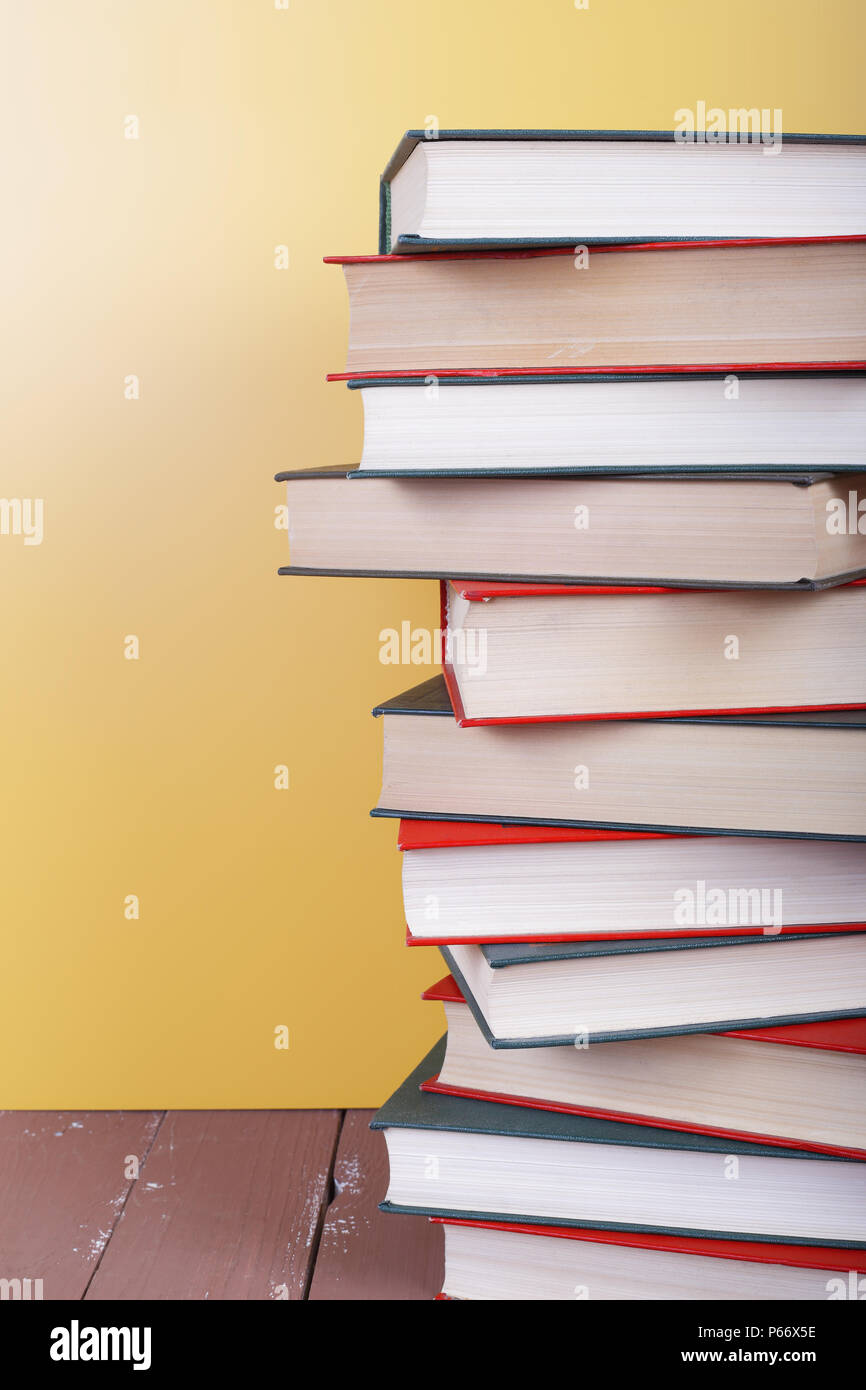 Wissenschaft und Bildung - hohen Stapel Gruppe von bunte Bücher auf dem Holztisch und gelben Hintergrund. Stockfoto